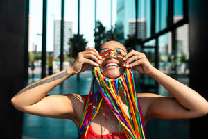 Smiling woman posing outdoors with colorful face decoration and red outfit