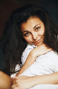 Portrait of a cheerful woman relaxing with pillow in bedroom at home