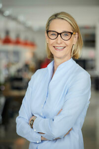 Confident businesswoman with eyeglasses smiling in modern office