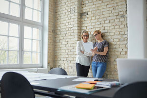 Women collaborating and discussing documents in modern office