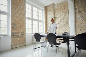 Businesswoman standing in modern office meeting room with sunlight