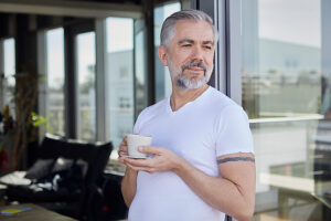 Mature man relaxing with coffee on a balcony in the morning
