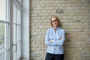 Confident businesswoman standing by window in modern office