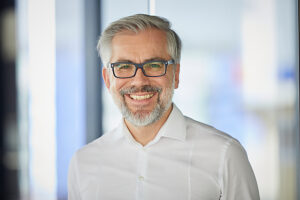 Smiling businessman with beard and glasses in modern office portrait