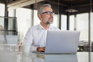 Businessman with glasses working on laptop in modern office