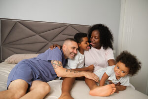 Family playing and laughing together on bed in bedroom
