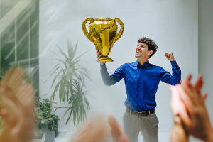 Businessman celebrating with trophy and applause in modern office