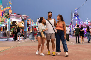 Group of friends laughing and walking together at a lively fair at night