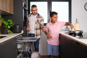 Father and son working together in modern kitchen helping with chores