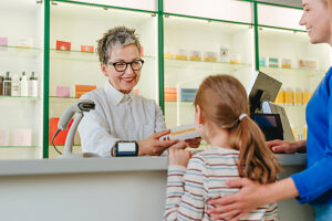 Pharmacist handing medicine to family at pharmacy counter smiling