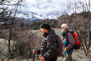 Friends hiking with trekking poles in snowy Pyrenees mountains in winter