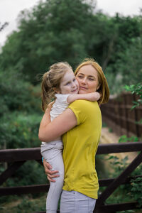 Mother hugging daughter outdoors in summer park
