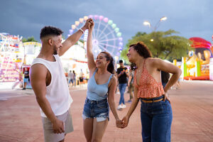 Friends enjoy amusement park rides together at an outdoor fair
