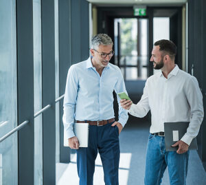 Business professionals communicating and collaborating in office hallway