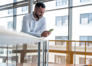 Professional in office smiling while checking mobile message
