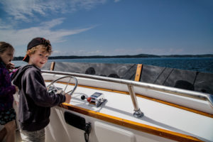 Canada, New Brunswick, St. Andrews by the Sea, ship excursion, boy on the helm of a motorboat Canada, New Brunswick, St. Andrews by the Sea, ship excursion, boy on the helm of a motorboat