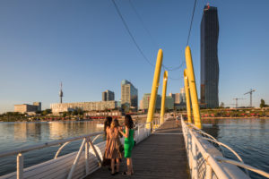 View from Copa-Steg to the leisure area CopaBeach on the New Danube, behind the buildings of the Danube City with the striking DC-Tower 1, 22nd district, Donaustadt, Vienna, Austria View from Copa-Steg to the leisure area CopaBeach on the New Danube, behind the buildings of the Danube City with the striking DC-Tower 1, 22nd district, Donaustadt, Vienna, Austria