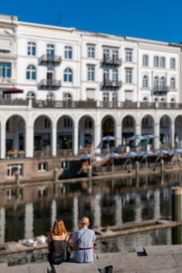 Two women sitting by the Alster, looking at Alsterhaus, Hamburg, Germany Two women sitting by the Alster, looking at Alsterhaus, Hamburg, Germany