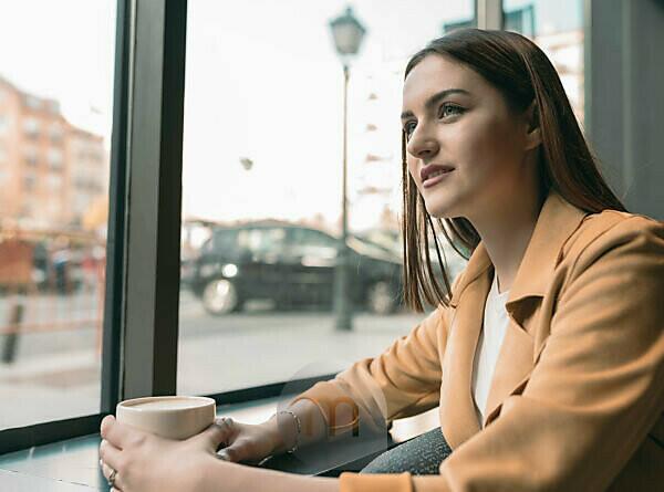 Smiling woman with coffee cup sitting on jetty stock photo