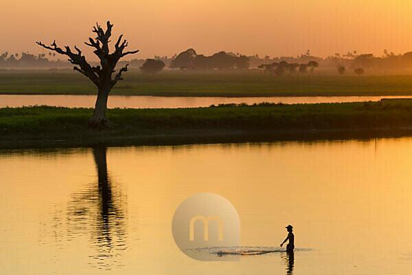 Fisherman throwing fishing net at Taungthaman Lake against