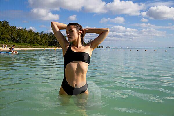 Foto de Sexy young woman in bikini posing n evening outdoor on the tropic  island beach taking off her clothes do Stock
