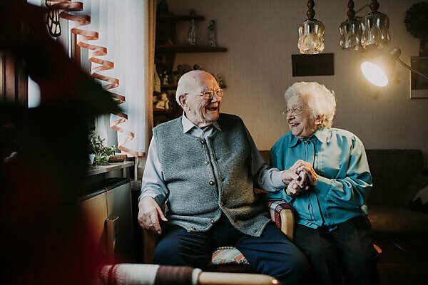 older couple sits laughingly in the living room