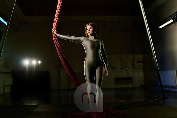 Two young female aerial acrobats practicing the splits on silk