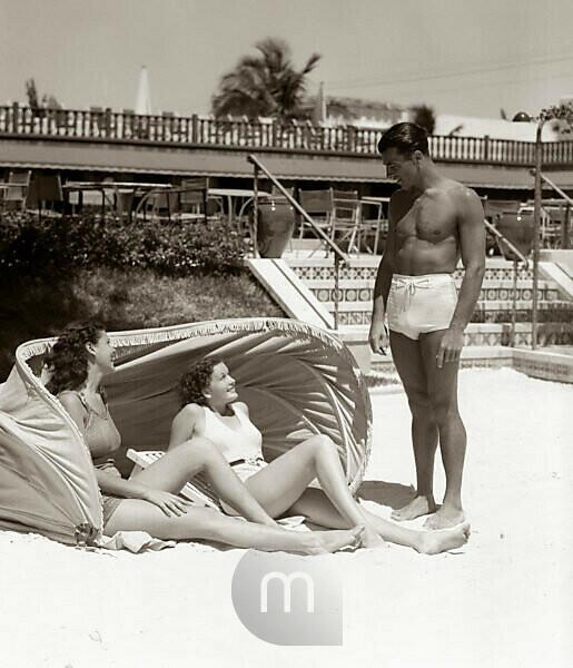 Three young women wearing bikinis on the beach - SuperStock
