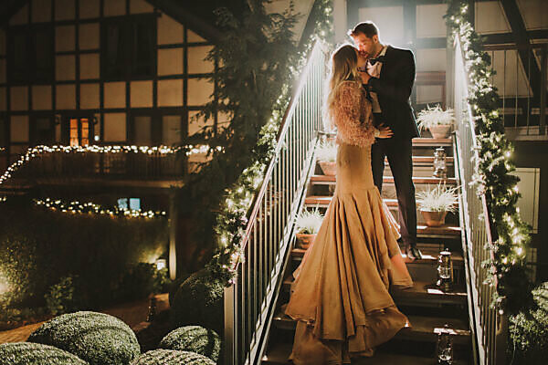 Bridal couple stand on a staircase and kiss each other