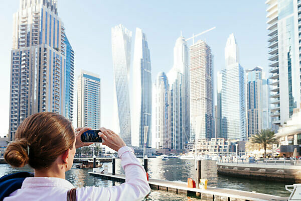 Dubai skyscrapers with Dubai Marina, female tourist taking a picture