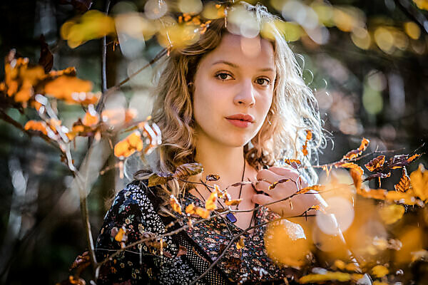 young woman with blond hair in the forest, serious and thoughtful look