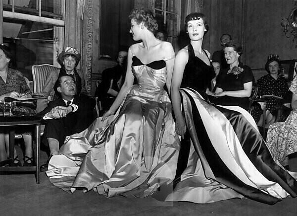 Bildagentur | mauritius images | At a fashion show in Saville Row Hardy  Amies is seated on the floor looking at two mannequins wearing dresses from  Charles James\'s collection. 22 July 1949