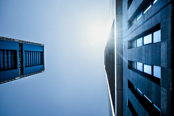 Blue cold tones colors of skyscrapers with sunlight - looking up perspective, city view of offices and financial district with bank and insurance people at work