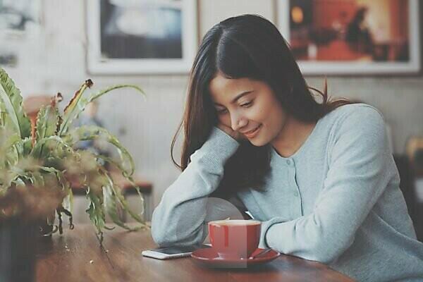 Smiling woman with coffee cup sitting on jetty stock photo